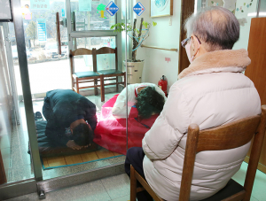 양로원 유리문 넘어 어머님께 세배하는 아들